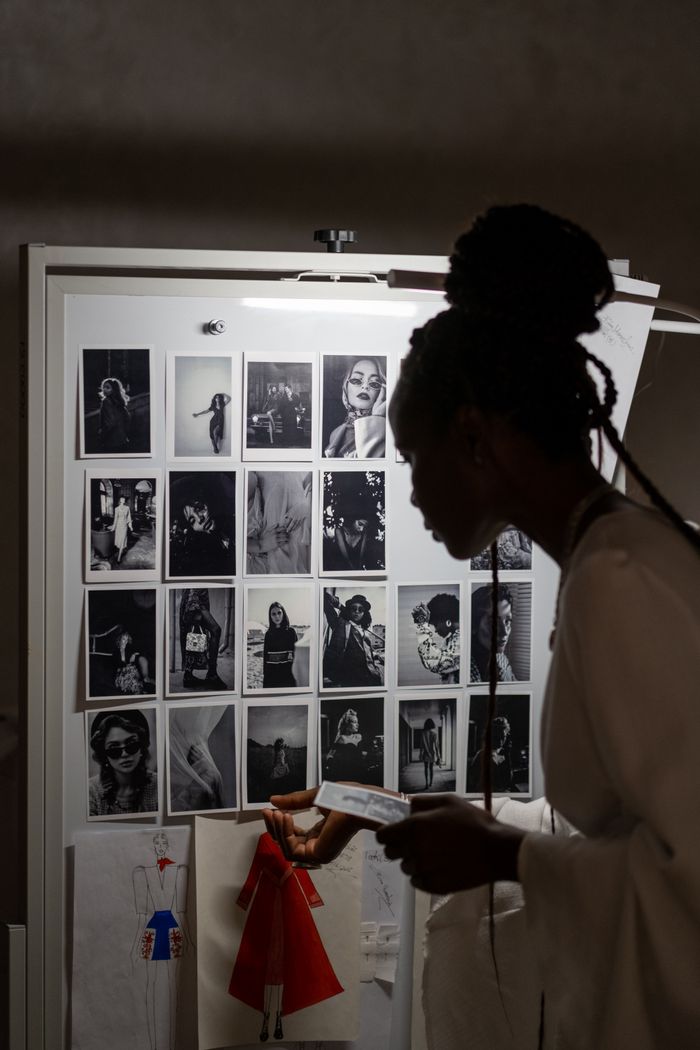 A fashion designer’s silhouette studying a creative mood board packed with fashion sketches and photographs.